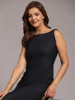 Woman in a sleeveless black dress with wavy hair and subtle jewelry, posing elegantly