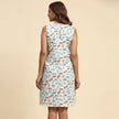 Woman wearing sleeveless white dress with colorful quirky print, viewed from the back