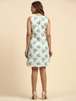 Woman in sleeveless printed dress with leaf pattern, standing on beige background