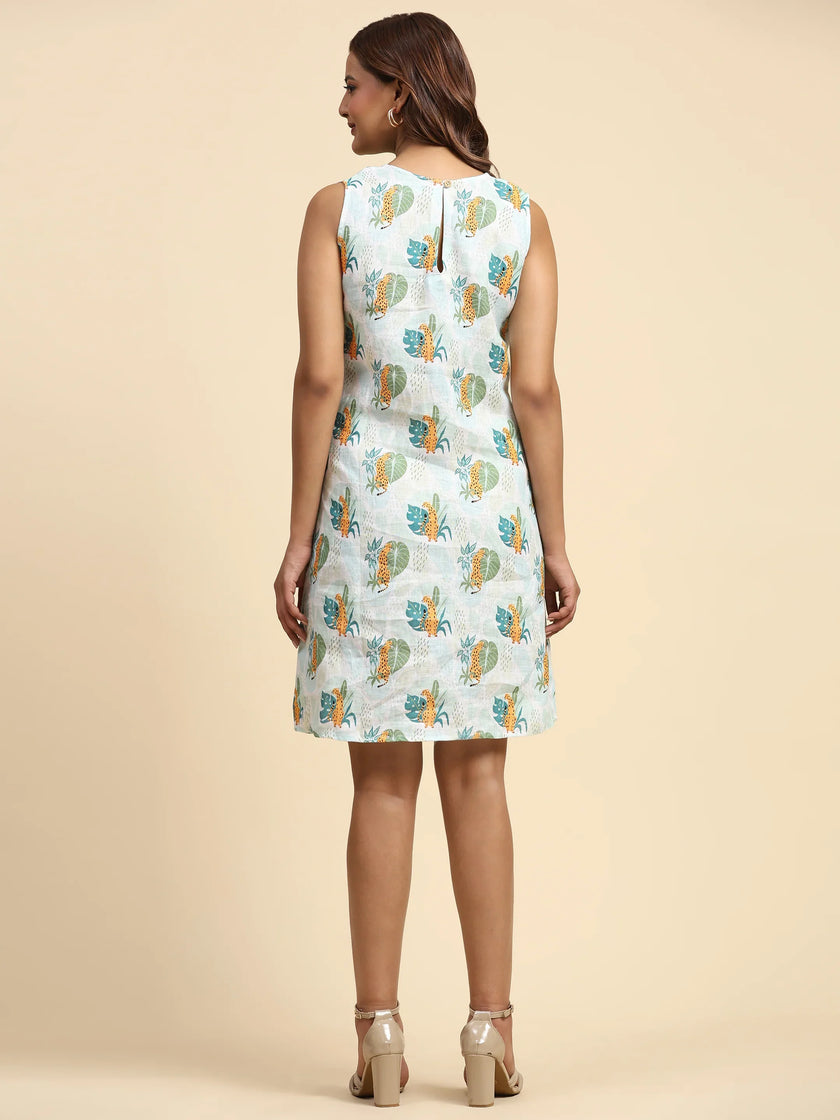 Woman in sleeveless printed dress with leaf pattern, standing on beige background