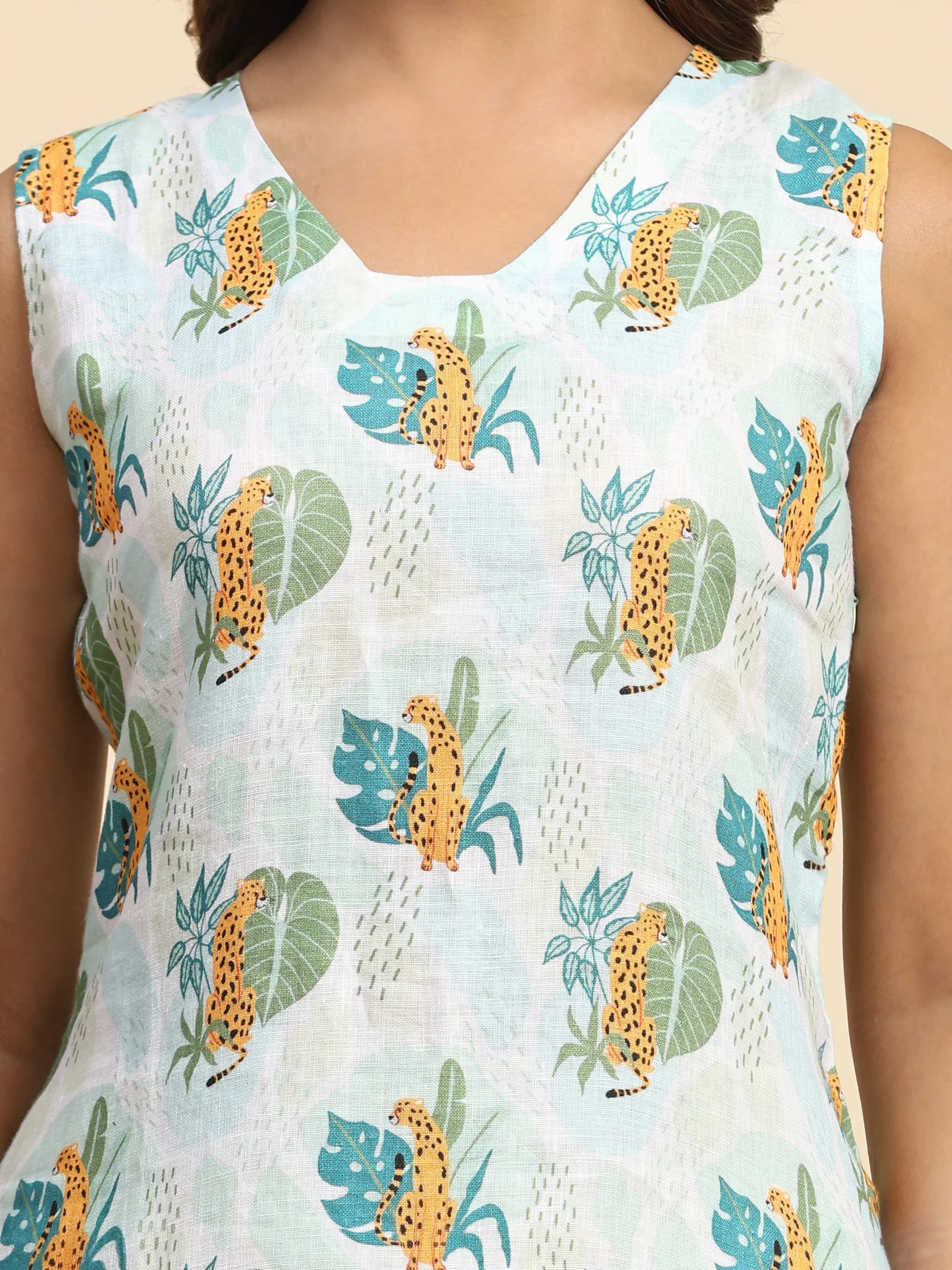 Sleeveless dress with cheetah and leaf print on light blue fabric, close-up view