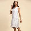Woman in sleeveless white floral dress with subtle print, modern fashion on beige background