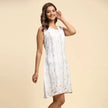 Woman wearing sleeveless white floral dress, modern fashion, neutral background