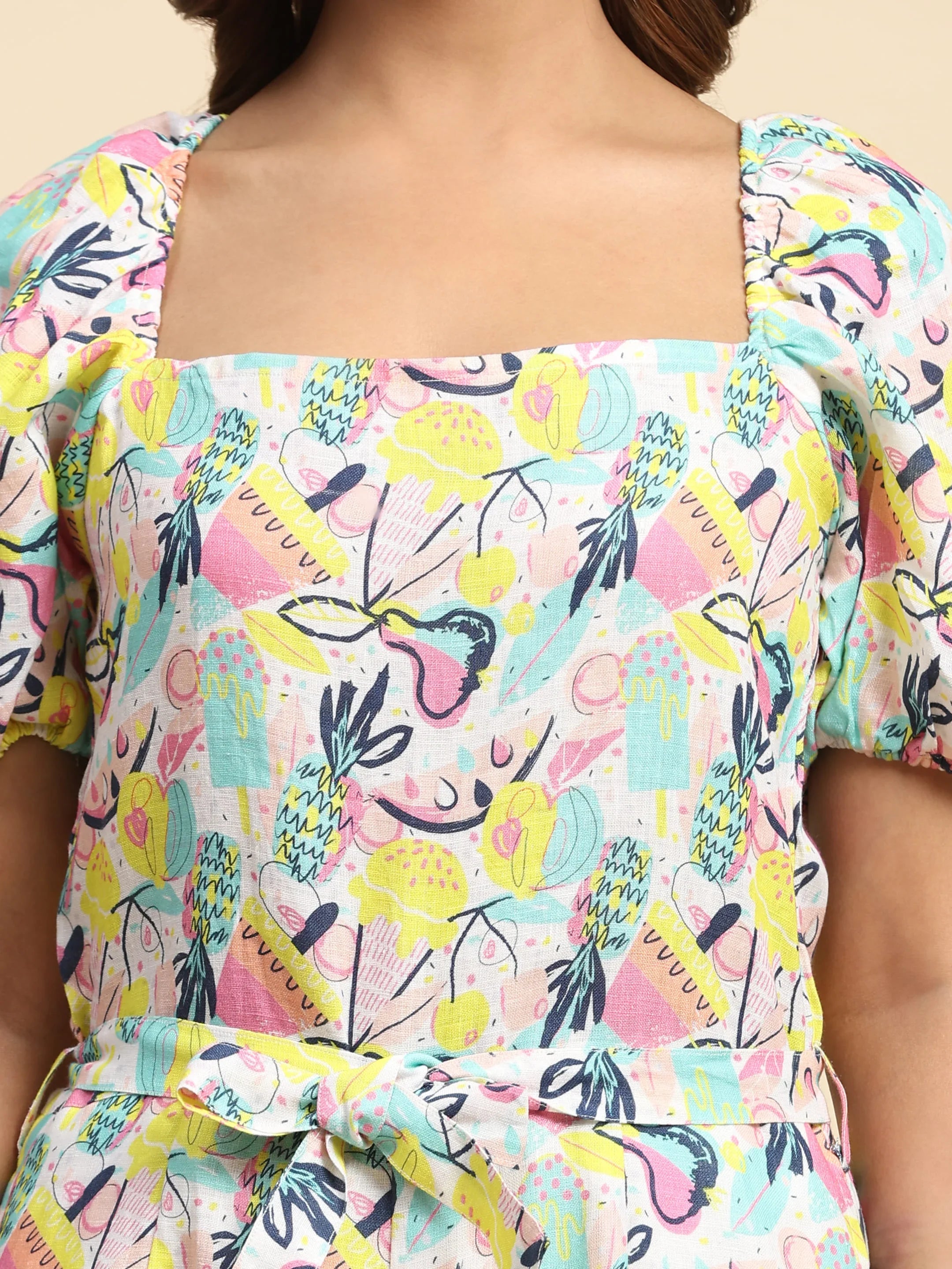 Woman wearing a square-neck dress with colorful abstract fruit print and puff sleeves.