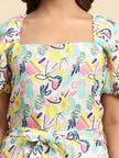 Woman wearing a square-neck dress with colorful abstract fruit print and puff sleeves.