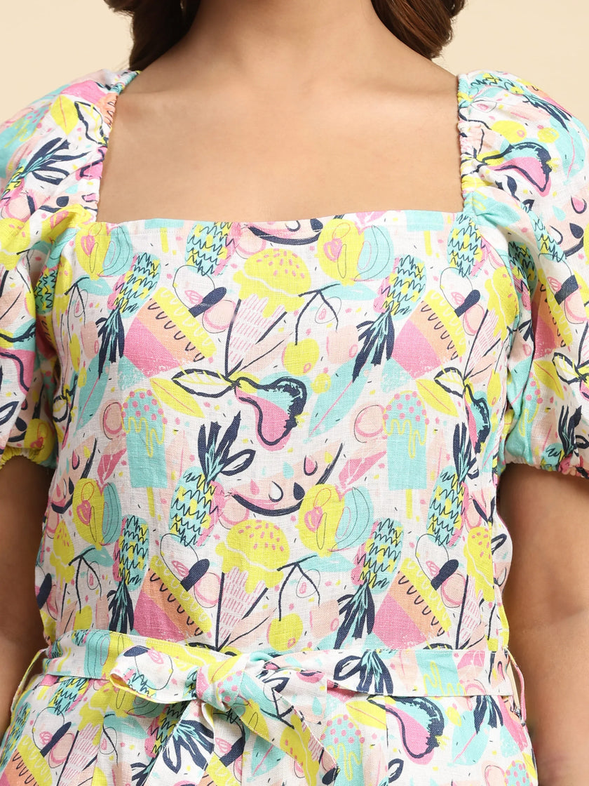 Woman wearing a square-neck dress with colorful abstract fruit print and puff sleeves.