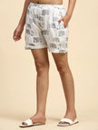 Woman wearing white printed shorts with grey elephants and white sandals