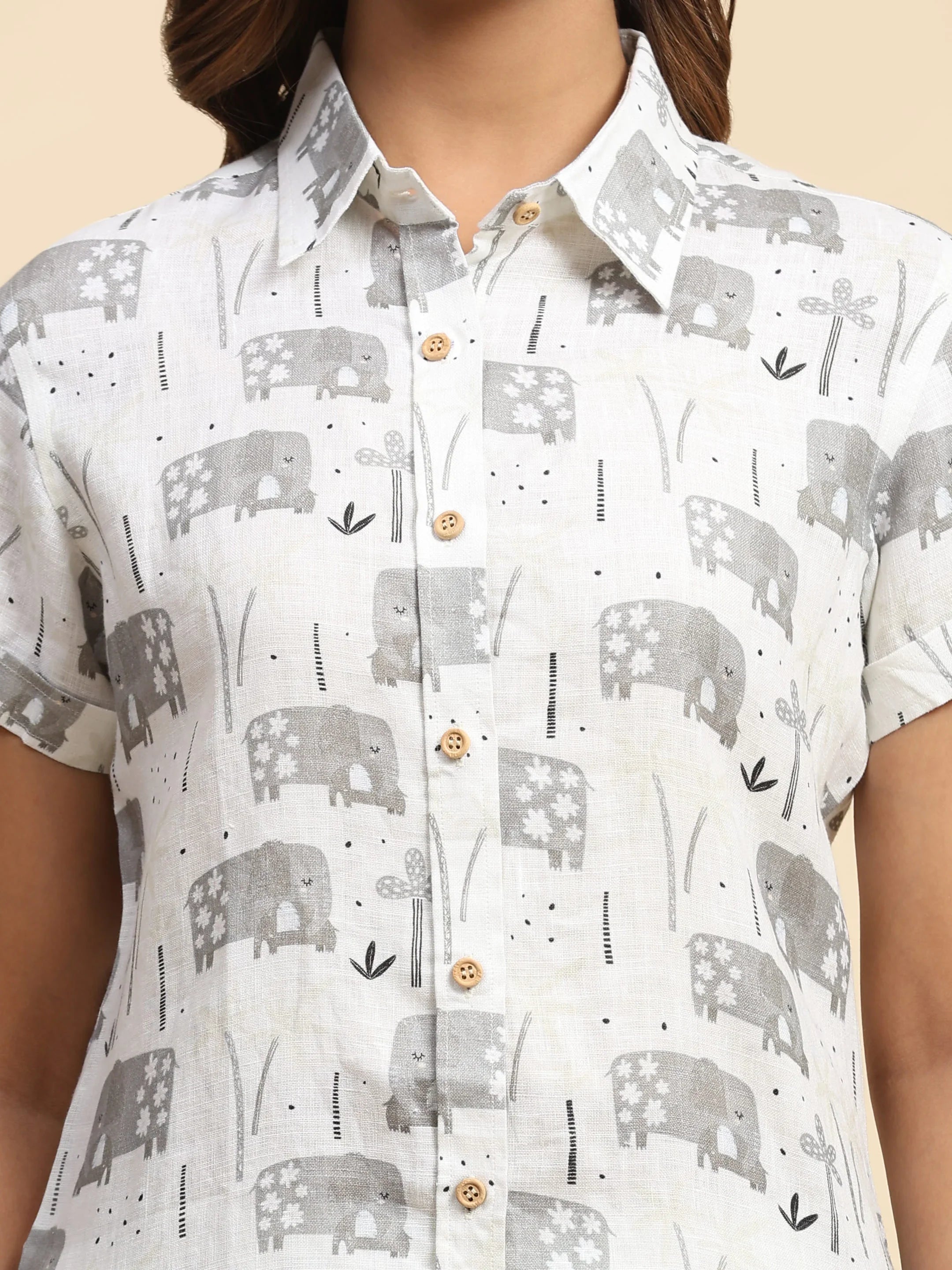 White collared shirt with gray elephant and floral print, short sleeves, wooden buttons