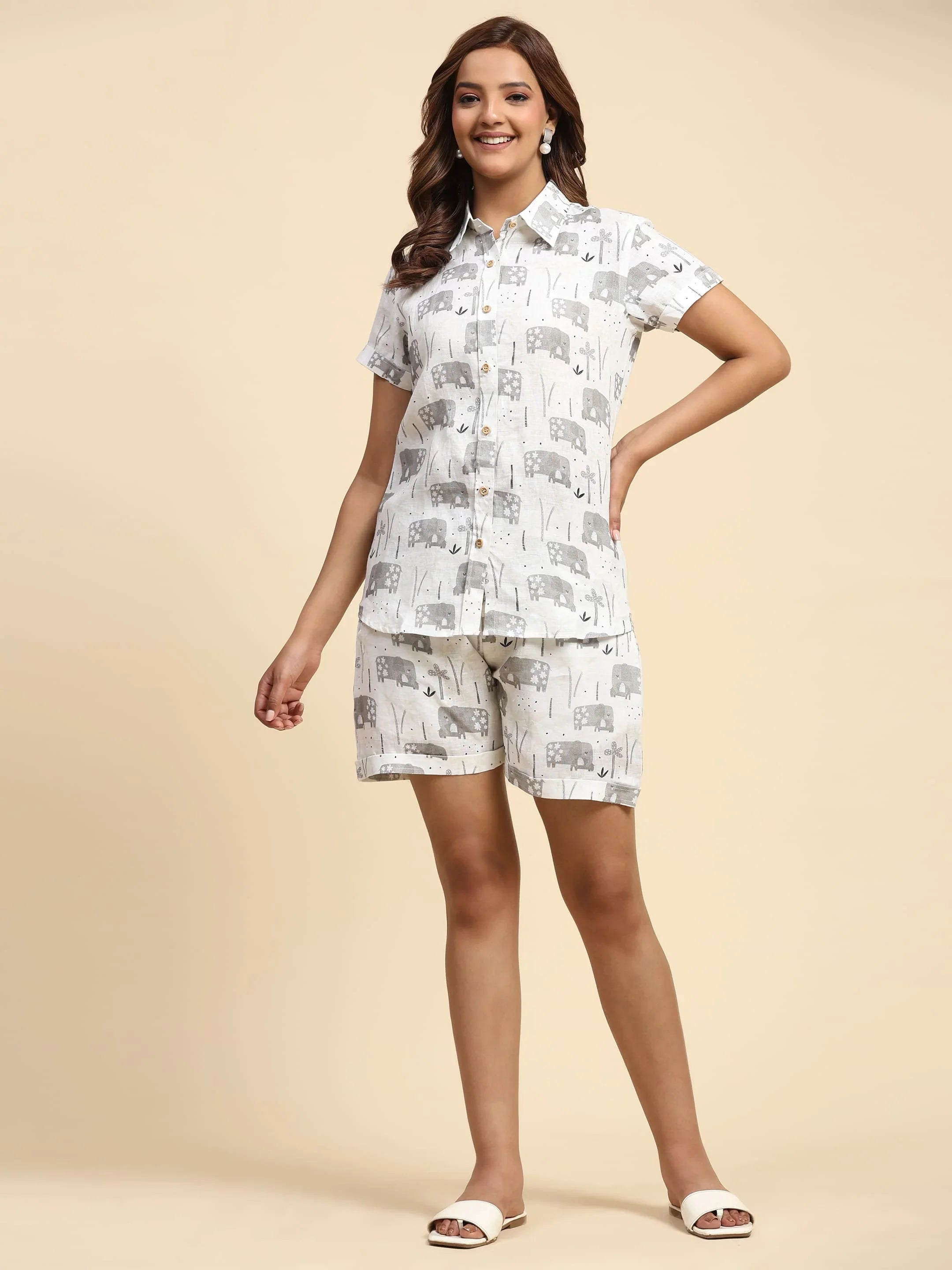 Woman wearing matching white shirt and shorts with grey elephant print, neutral background