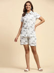 Woman wearing matching white shirt and shorts with grey elephant print, neutral background