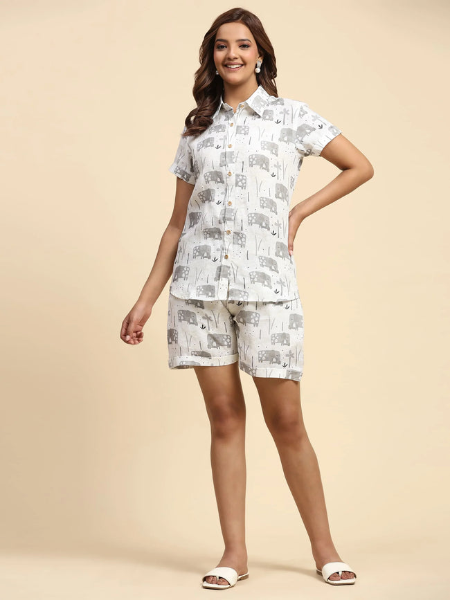 Woman wearing matching white shirt and shorts with grey elephant print, neutral background