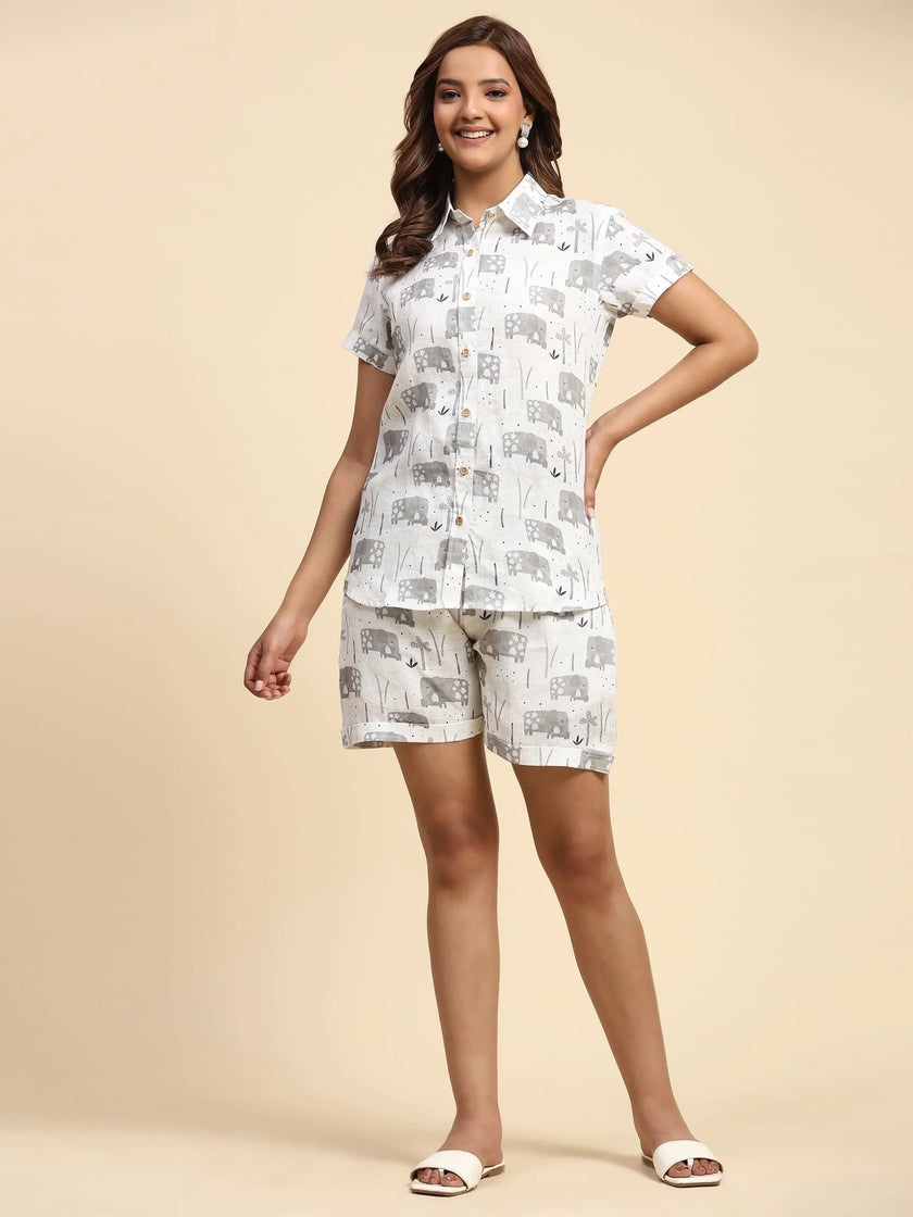Woman wearing matching white shirt and shorts with grey elephant print, neutral background