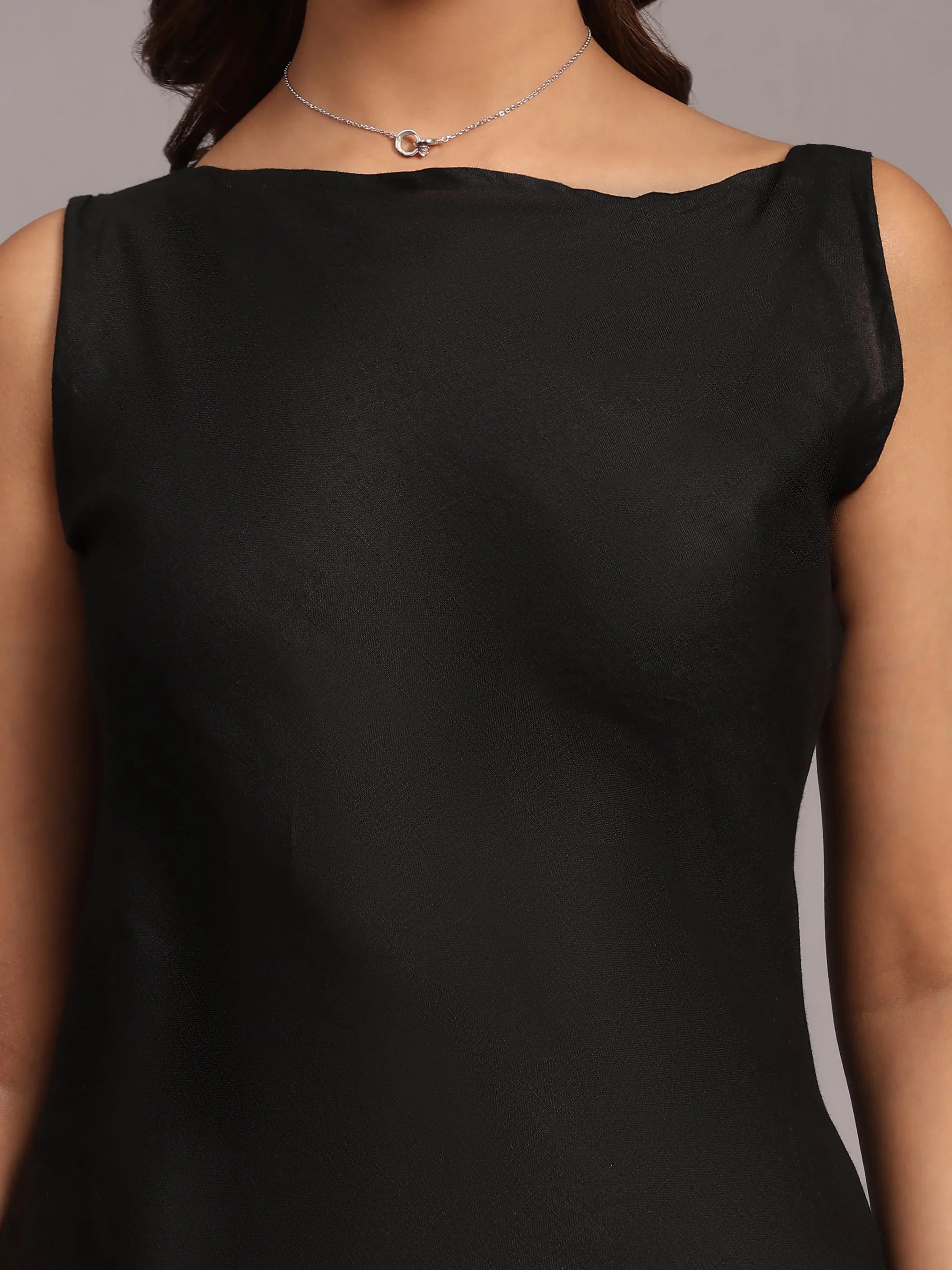 Woman wearing sleeveless black dress and delicate silver necklace