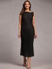 Woman in sleeveless black midi dress and heels posing against a neutral background