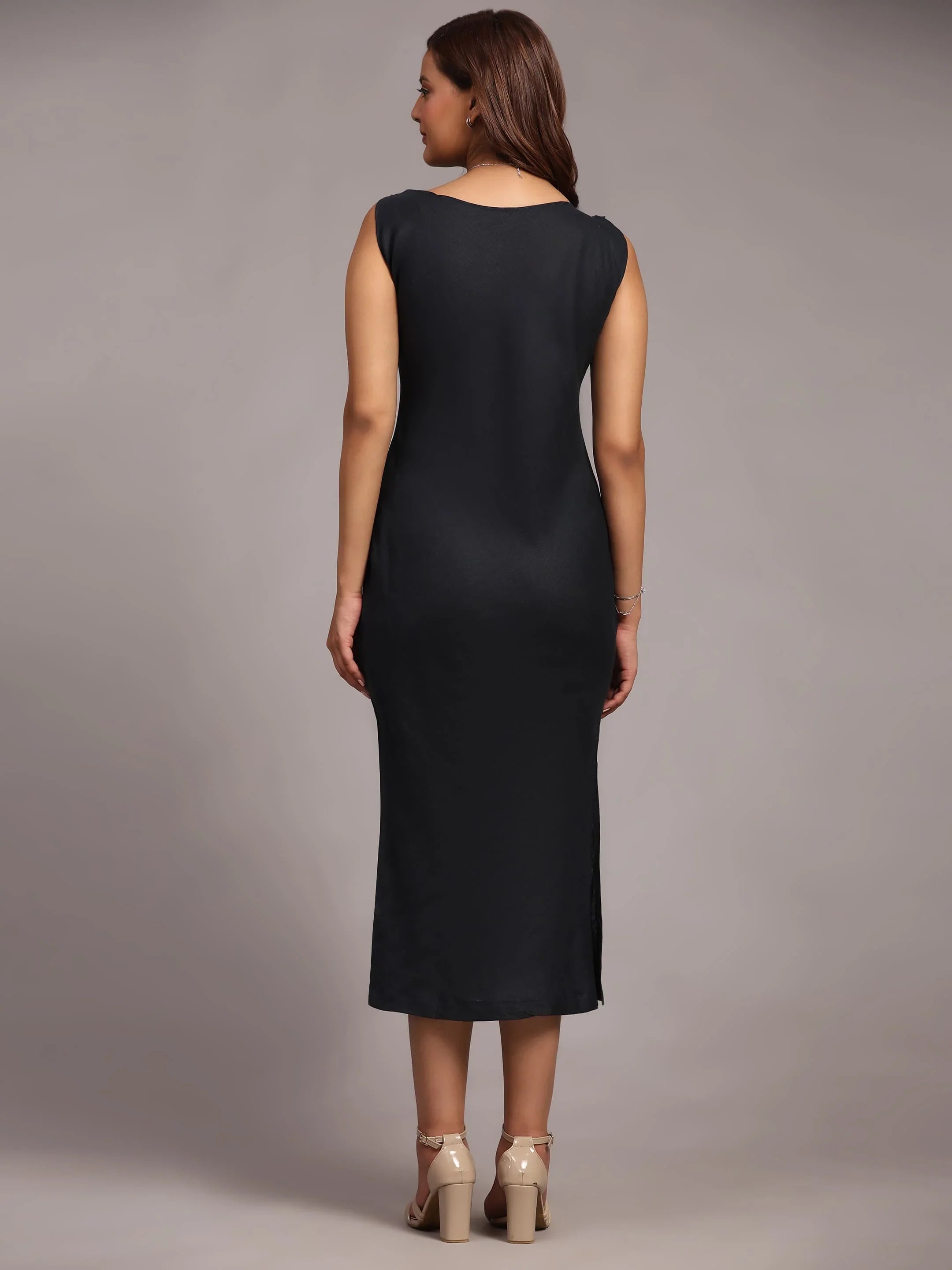 Woman in sleeveless black midi dress and heels, back view, in studio setting