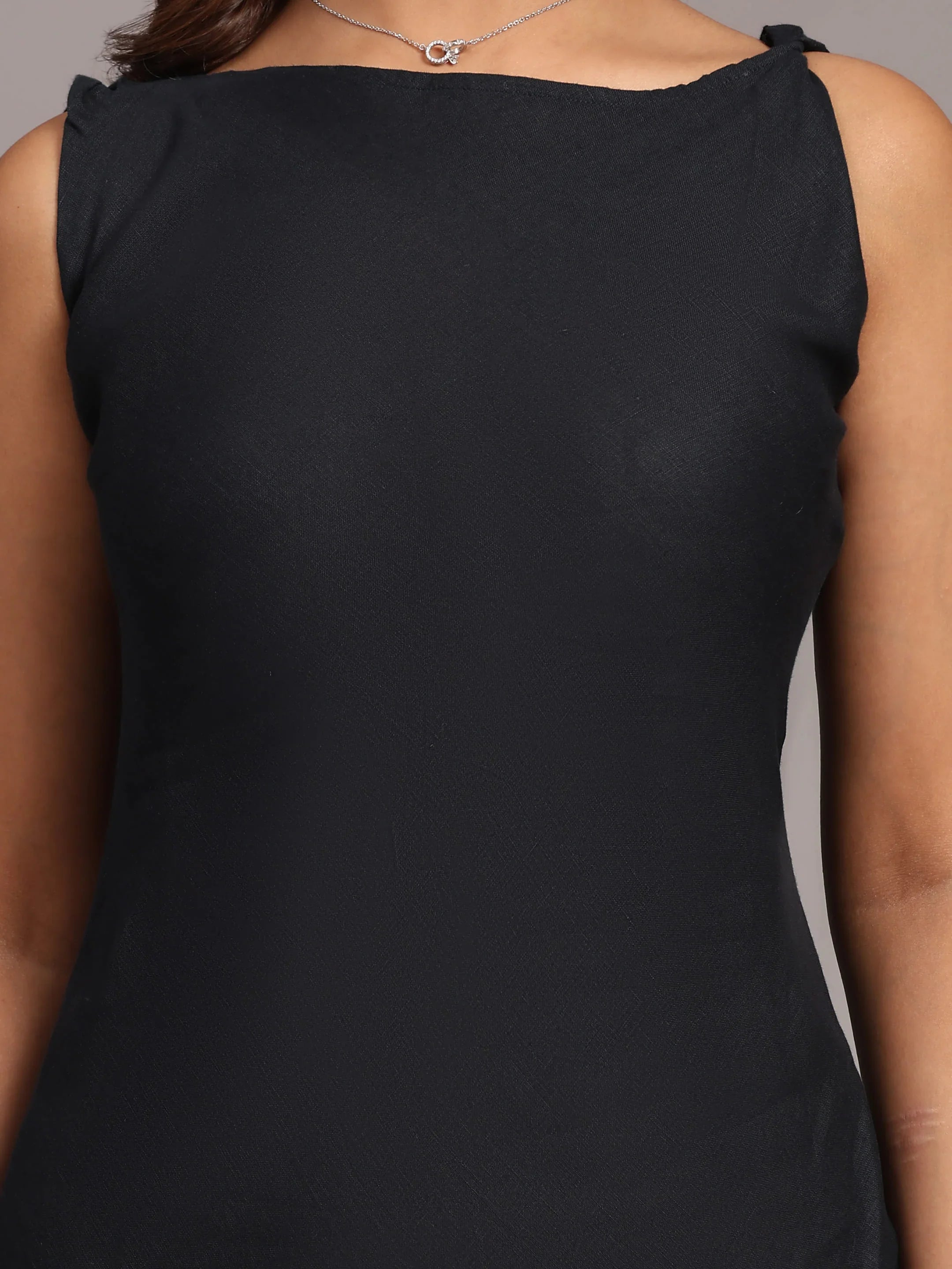 Sleeveless black dress with boat neckline, close-up on upper torso, elegant adult fashion