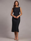 Woman wearing a sleeveless, black midi dress with a bateau neckline, posing in studio
