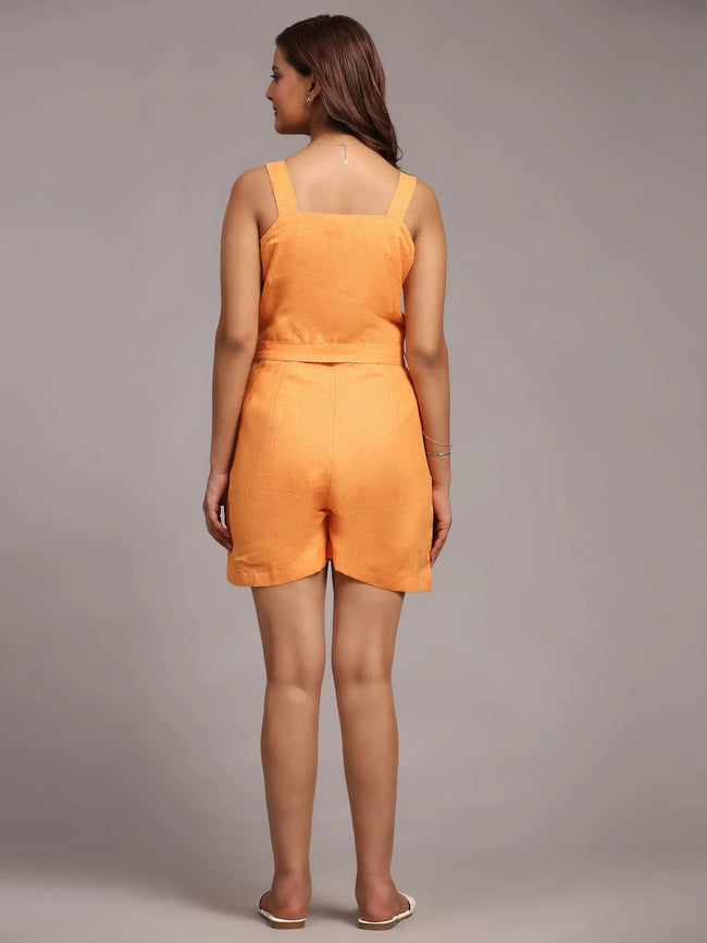 Woman wearing an orange sleeveless top and matching shorts, back view, studio setting