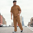 Man in modern tan button-up shirt and matching pants posing on city street