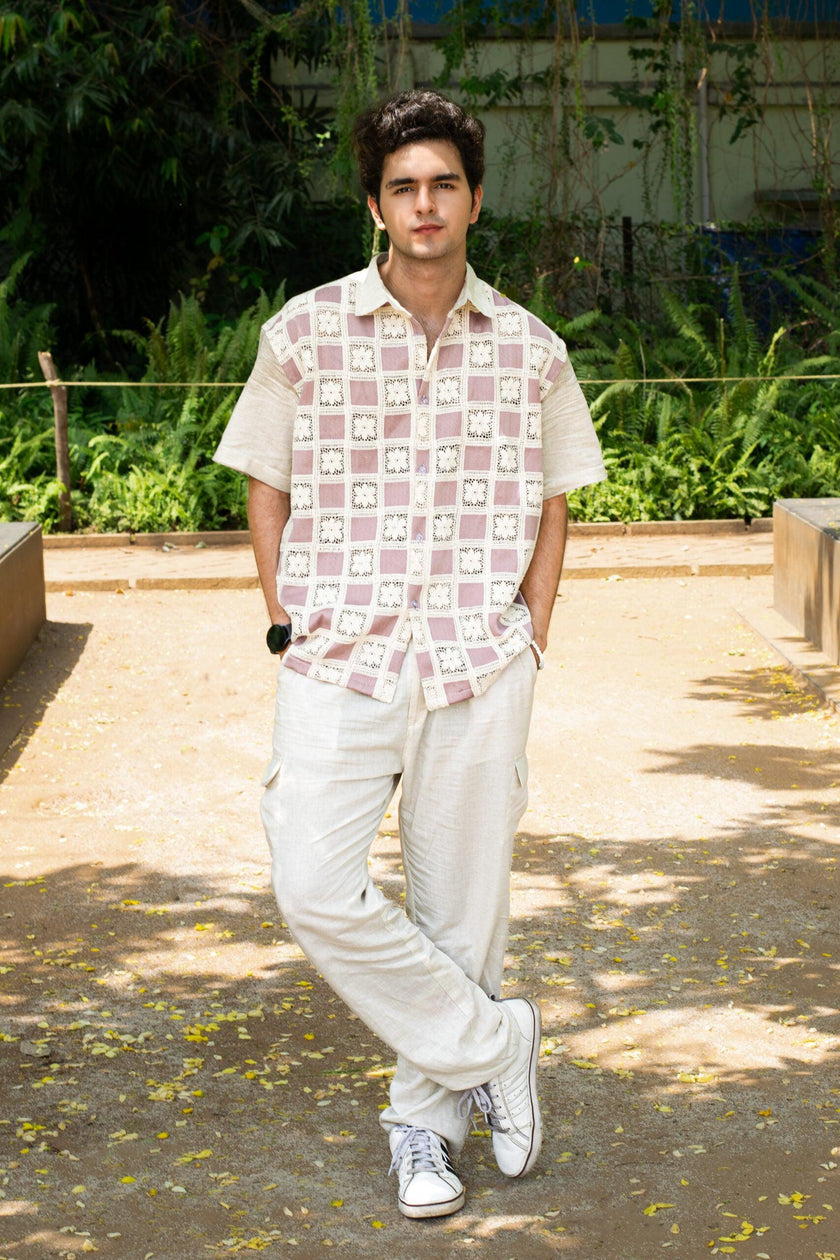 Man in a patterned short-sleeve shirt and light trousers posing outdoors in casual fashion