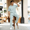 Man in light blue short sleeve shirt and matching trousers, seated outdoors, stylish look
